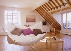 a white hammock hanging from the ceiling in a room with wood flooring