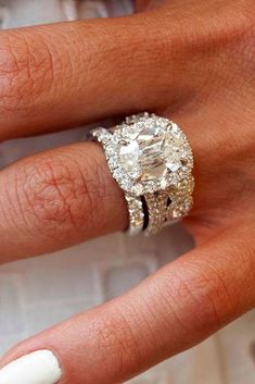 a woman's hand with a white manicured nails and a ring on it