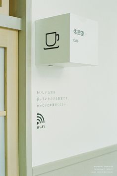 a white wall mounted on the side of a building with a coffee cup sign above it