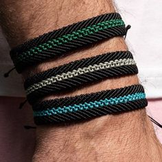 a close up of a person's arm wearing three different colored bracelets