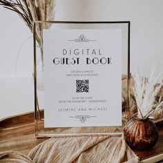 a digital guest book sitting on top of a wooden table next to a vase with dried grass