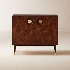 a wooden cabinet with two brass knobs on the front and bottom, against a white background