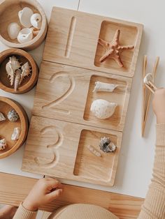 a child's hands on a wooden tray with seashells and starfish