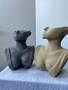 two sculptures sitting on top of a white table