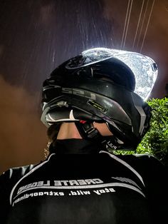 a man wearing a helmet and standing in the rain