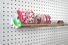 several rolls of red and white tape are hanging on a peg board