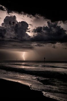 the sun is shining through dark clouds over the ocean and lighthouses in the distance