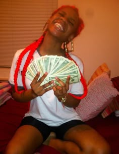 a woman sitting on top of a bed holding a fan of money in her hands