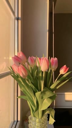 a vase filled with pink tulips on top of a table