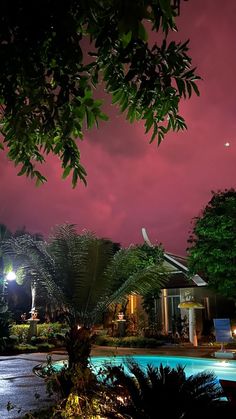 the night sky is lit up over a house and pool in front of some trees