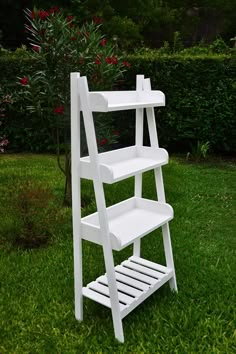 a white shelf sitting on top of a green grass covered field next to a bush