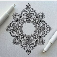 a pen and some ink sitting on top of a piece of paper with an ornate design