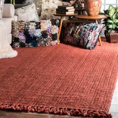 a red rug with fringes on the floor in front of a couch and coffee table