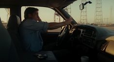 a man sitting in the driver's seat of a car next to power lines