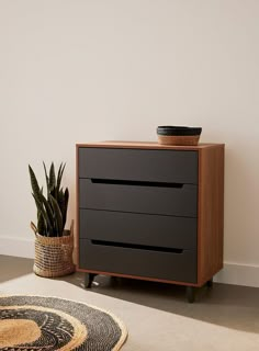 a black dresser sitting next to a potted plant