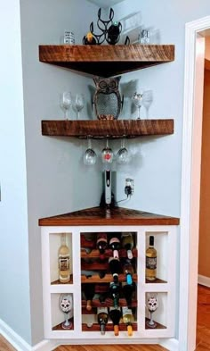 a wine rack in the corner of a room with bottles and glasses on top of it