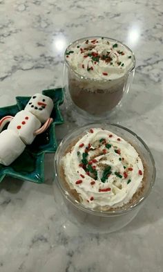 two desserts with frosting and sprinkles are on the table next to each other