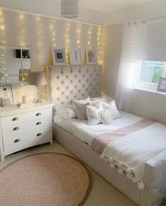 a bedroom with white furniture and lights on the wall above the bed, along with a round rug