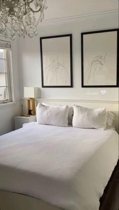 a white bed with two framed pictures above it