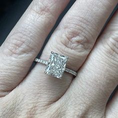 a woman's hand with a diamond ring on top of her finger and an engagement band