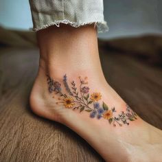 a woman's foot with flowers and leaves on the bottom part of her body