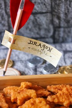 a wooden box filled with fried food next to a red flag on top of a table