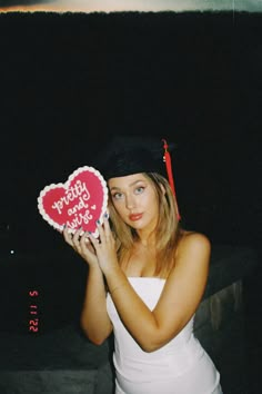 a woman holding up a heart shaped cake