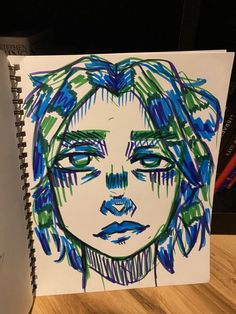 a drawing of a woman's face with blue and green hair