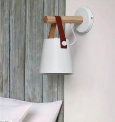 a white lamp hanging from the side of a wall next to a bed with pillows