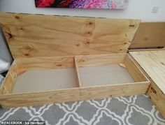 an open wooden box sitting on top of a floor next to a rug and painting