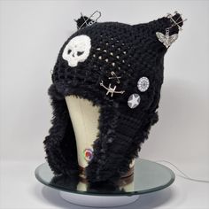 a knitted skull and crossbone hat with earring pins on it's head