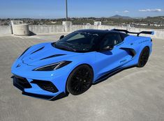 a blue sports car is parked in an empty lot with no one around it,