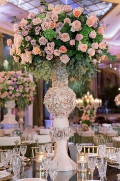 a tall vase filled with lots of pink flowers on top of a dining room table