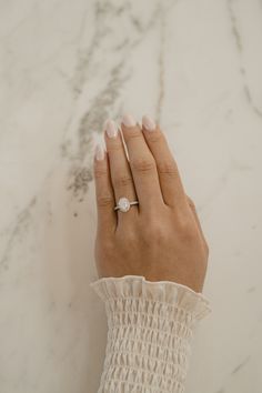 a woman's hand with a diamond ring on her left wrist, resting against a marble surface