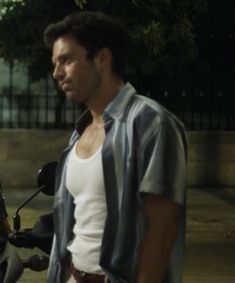 a man standing next to a motorcycle in front of a fenced area at night