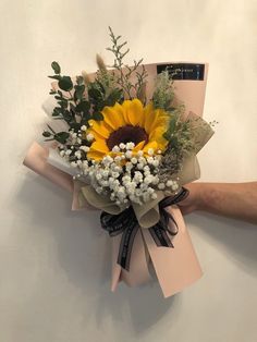 a bouquet of sunflowers and baby's breath is held up against a wall