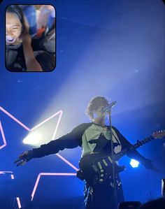 a man standing on top of a stage holding a guitar