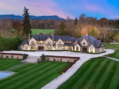 an aerial view of a large home with lots of grass and trees in the background