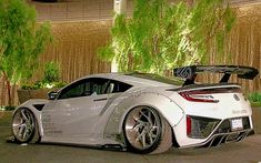 a white sports car parked in front of a building with trees on the side of it