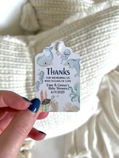 a person holding up a thank tag with sea animals on it