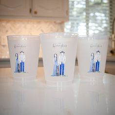 three plastic cups with pictures of people on them sitting on a counter top in a kitchen