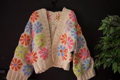 Crocheted cardigan with daisy squares, the base color is beige the flowers are orange, pink, purple, blue and green Cute Cosmetics, Crochet Bag Charm, Crochet Flower Squares, Crochet Diy Tutorial, Hanging Charms, Crochet Bag Tutorials, Crochet Bag Pattern Free, Crochet Blanket Designs, Crochet Daisy