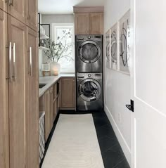 a washer and dryer in a small room with wood cabinets on either side