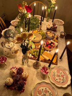 a table is set with plates, candles and flowers on it for a festive feast