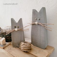 two wooden cats sitting on top of a table next to a ball of twine