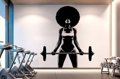 a woman with an afro is holding a barbell in a gym room wall decal