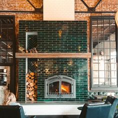 two people sitting at a table in front of a fireplace with logs stacked on it