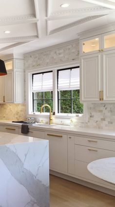 a kitchen with marble counter tops and white cabinets