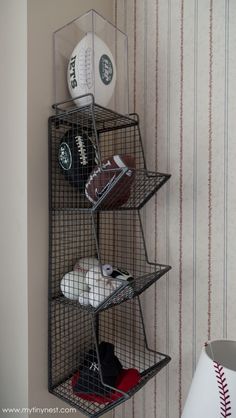 a wire shelf with baseballs, gloves and balls on it in a room that has striped walls