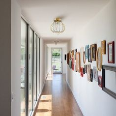 a long hallway with pictures on the wall next to glass doors and wooden flooring